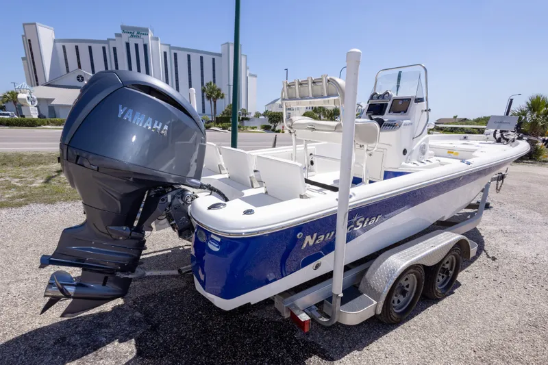 Slide: The Image of 2015 NauticStar 214 XTS boat with Yamaha engine on trailer, parked near a modern building. - 16
