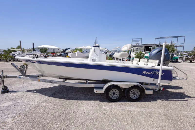 Slide: The Image of 2015 NauticStar 214 XTS boat on trailer, parked outdoors under clear blue sky. - 19