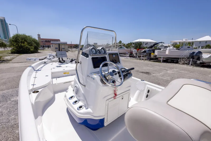 Slide: The Image of 2015 NauticStar 214 XTS boat interior with steering console and seating, parked outdoors. - 24