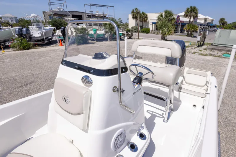 Slide: The Image of 2015 NauticStar 214 XTS boat interior with steering console and seating in a marina setting. - 41