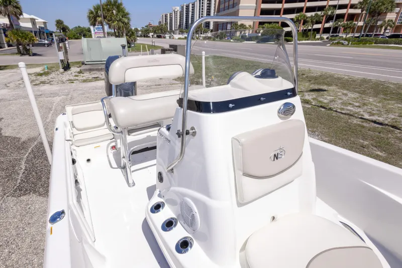 Slide: The Image of 2015 NauticStar 214 XTS boat interior with seating and console, parked near a road. - 42