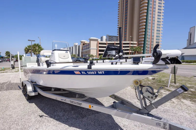 Slide: The Image of 2015 NauticStar 214 XTS boat on trailer, parked near tall buildings under clear blue sky. - 9