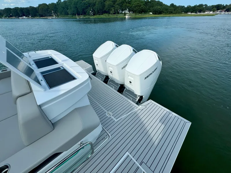 Slide: The Image of 2025 Cruisers Yachts 50 GLS Outboard with triple Mercury engines on a serene lake. - 17