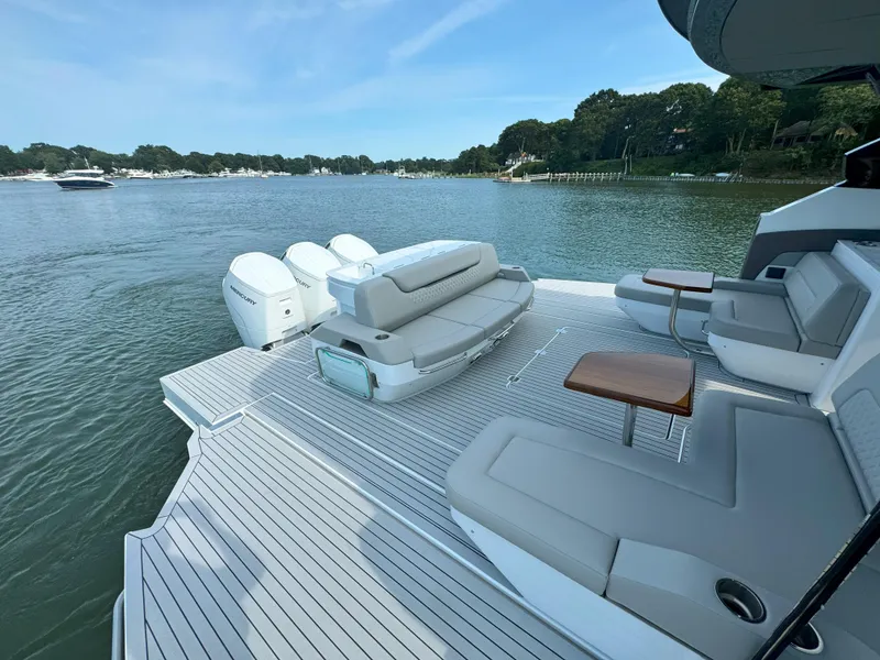 Slide: The Image of 2025 Cruisers Yachts 50 GLS Outboard, spacious deck with seating, on a serene lake. - 22