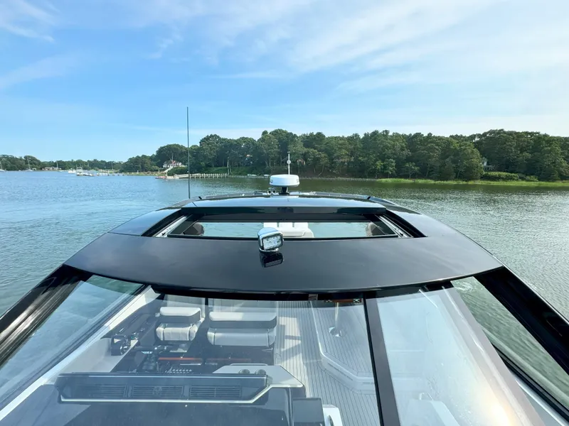 Slide: The Image of 2025 Cruisers Yachts 50 GLS on calm water with wooded shoreline. - 33
