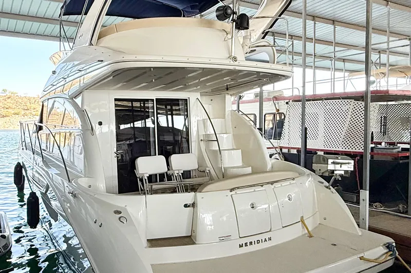 The Image of 2011 Meridian 391 Sedan yacht docked in a covered marina, showcasing sleek design and spacious deck. - 0