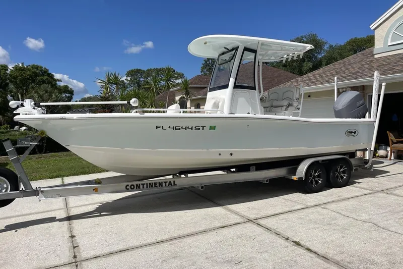 Slide: The Image of 2020 Sea Hunt BX 25 FS boat on trailer, parked in driveway under clear blue sky. - 11