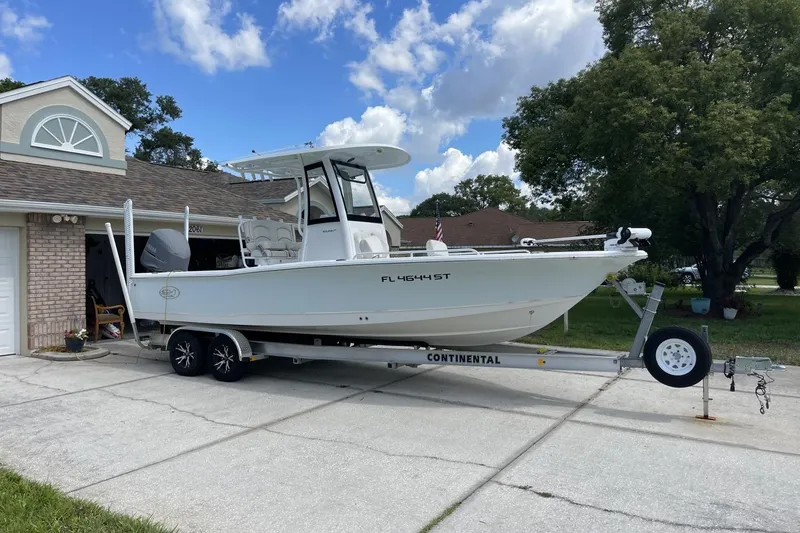 Slide: The Image of 2020 Sea Hunt BX 25 FS boat on trailer in driveway, clear sky background. - 2