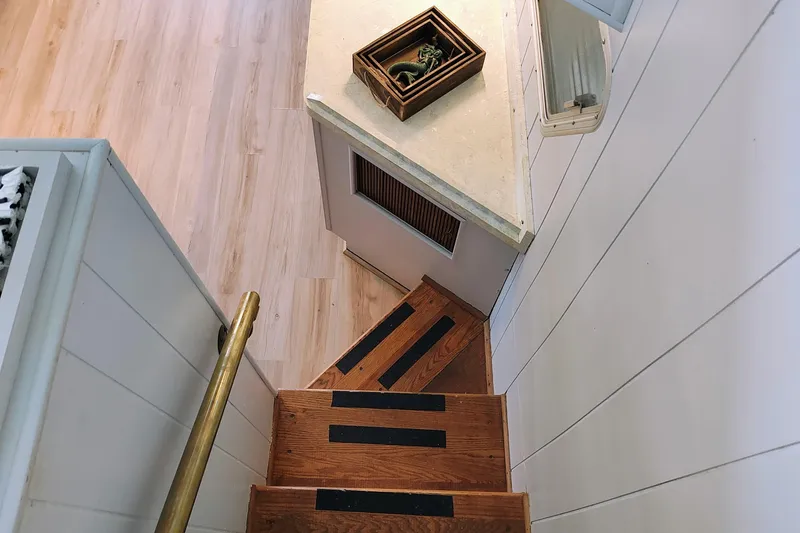 Slide: The Image of Aerial view of narrow wooden stairs with black anti-slip strips and a brass handrail. - 24