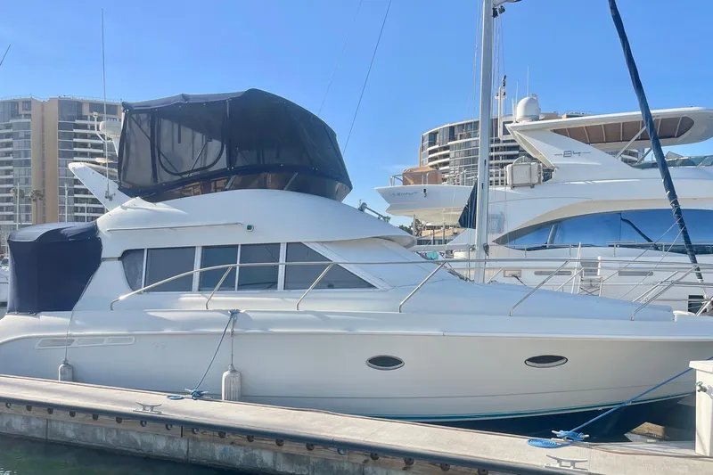Slide: The Image of 1995 Silverton 36 Convertible yacht docked at marina, with modern buildings in background. - 1