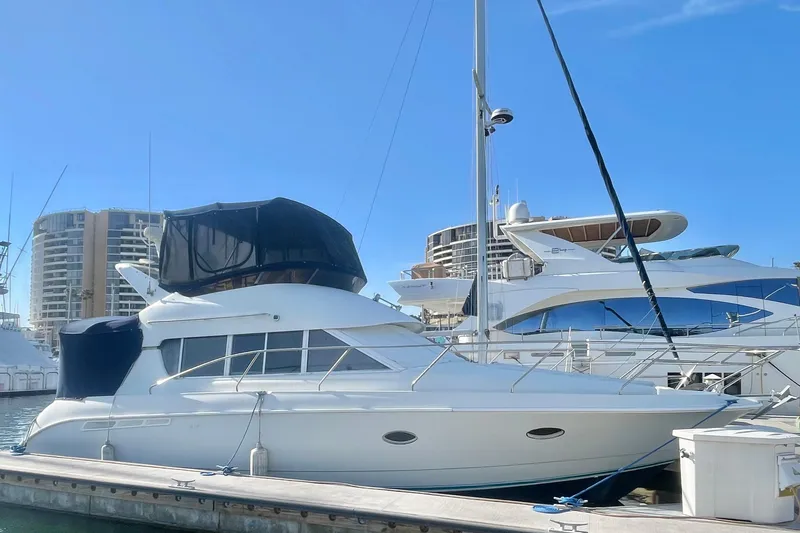 The Image of 1995 Silverton 36 Convertible yacht docked at marina under clear blue sky. - 2