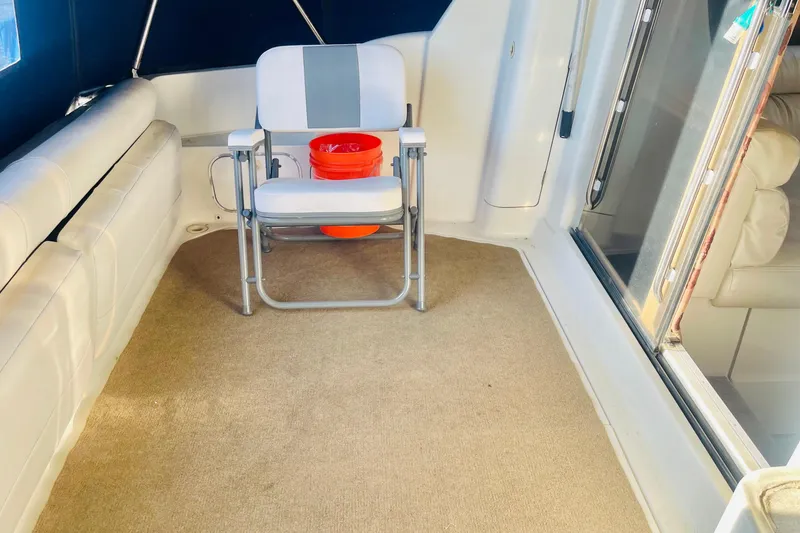 Slide: The Image of 1995 Silverton 36 Convertible boat interior with chair and orange bucket on carpeted floor. - 9