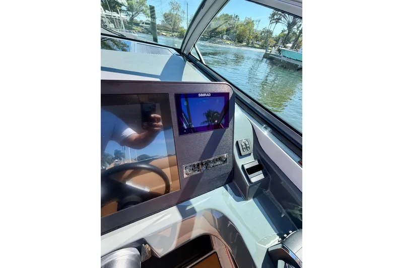 Slide: The Image of 2023 Aviara AV40 OB dashboard with navigation screen, docked by a scenic waterfront. - 23
