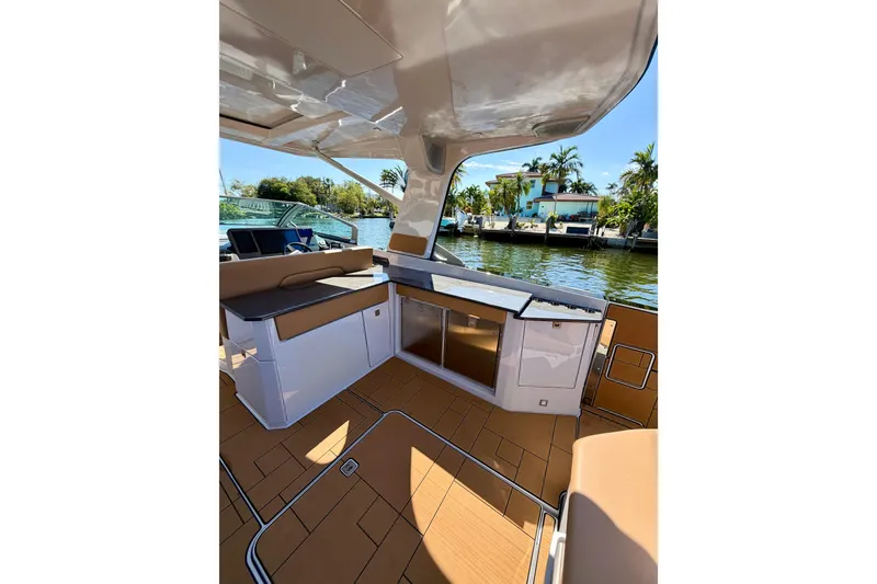 Slide: The Image of 2023 Aviara AV40 OB boat interior with seating and kitchenette, docked by waterfront homes. - 32