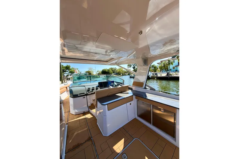 Slide: The Image of 2023 Aviara AV40 OB boat interior with modern helm and seating, docked by a scenic waterfront. - 35