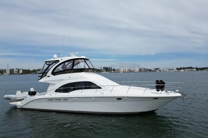 The Image of 2007 Sea Ray 52 Sedan Bridge yacht on calm water, cityscape in background. - 0