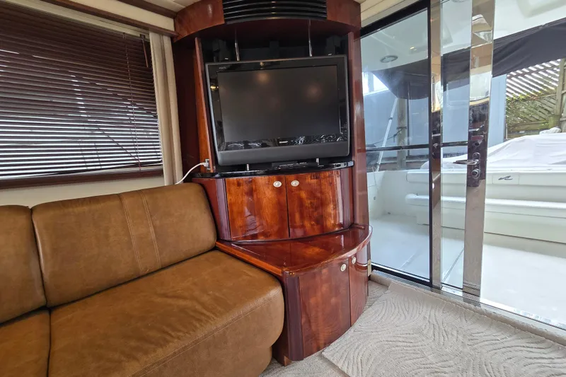 Slide: The Image of Interior of 2007 Sea Ray 52 Sedan Bridge with TV, brown sofa, and glass door. - 38