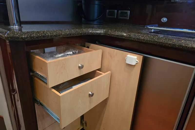 Slide: The Image of 2007 Sea Ray 52 Sedan Bridge kitchen with open wooden drawers and granite countertop. - 51