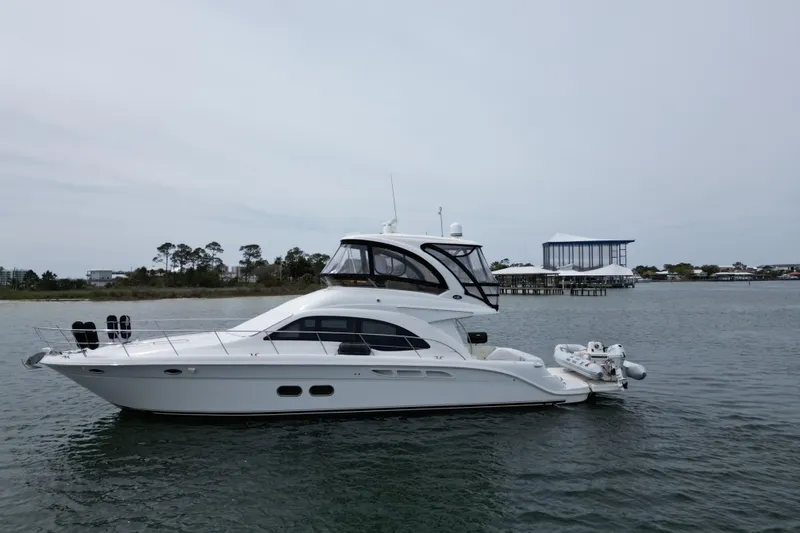 Slide: The Image of 2007 Sea Ray 52 Sedan Bridge yacht on calm water near shoreline. - 6