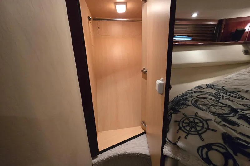 Slide: The Image of 2007 Sea Ray 52 Sedan Bridge cabin with open closet and nautical-themed bedding. - 64