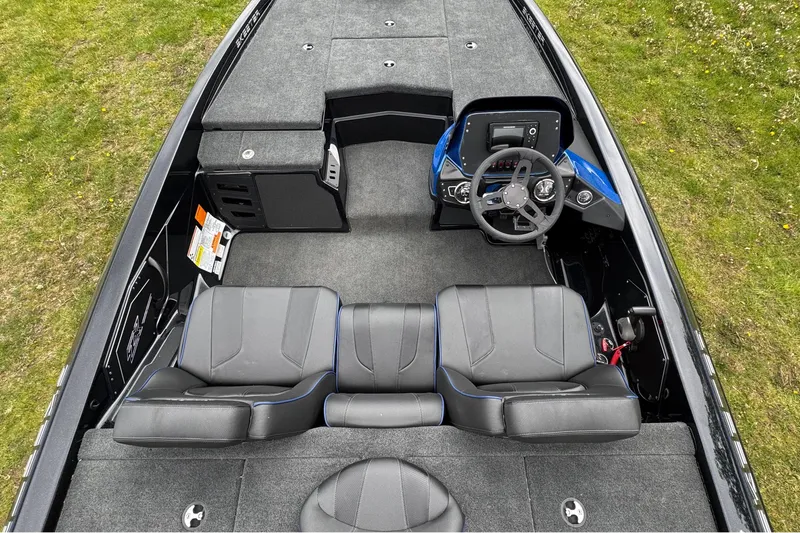 Slide: The Image of 2022 Skeeter ZX150 boat interior with steering wheel and seating on grassy background. - 12