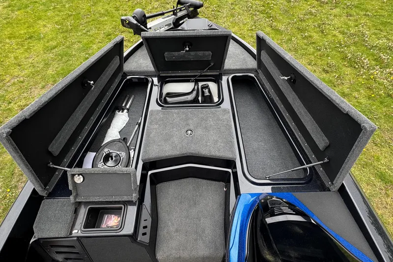 Slide: The Image of 2022 Skeeter ZX150 boat interior with open storage compartments on grassy background. - 14