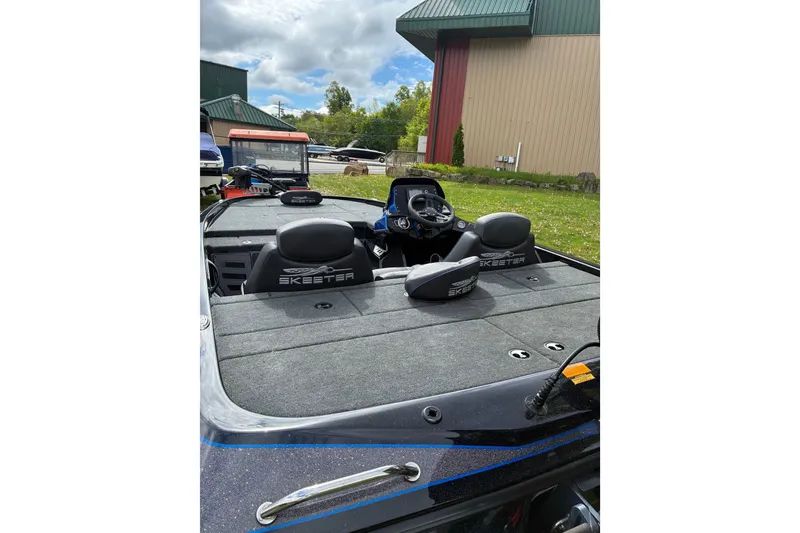 Slide: The Image of 2022 Skeeter ZX150 boat interior with steering console and seating, outdoors under cloudy sky. - 4