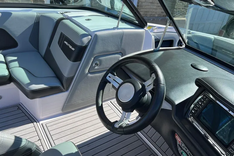 Slide: The Image of Interior of a 2014 Nautique Super Air Nautique 210 boat, featuring steering wheel and seating. - 11