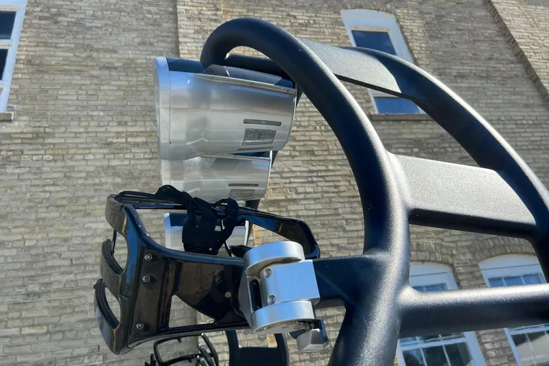 Slide: The Image of 2014 Nautique Super Air Nautique 210 wakeboard tower with speakers, against brick building backdrop. - 13