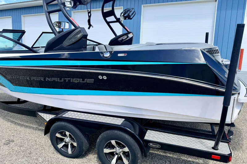Slide: The Image of 2014 Nautique Super Air Nautique 210 boat on trailer, blue and black design. - 13