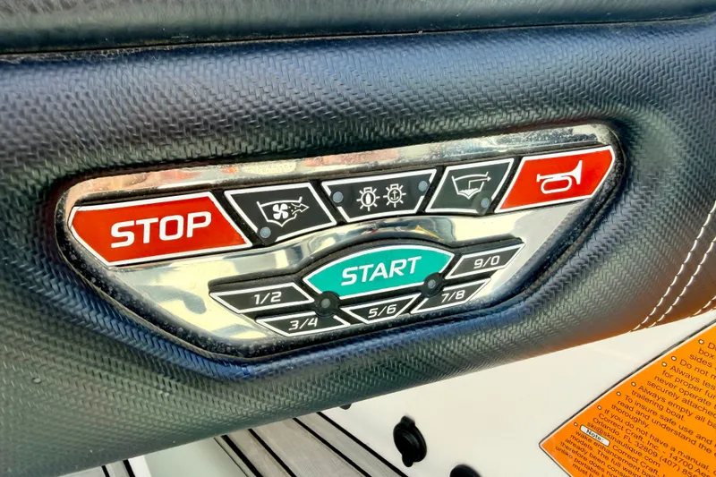 Slide: The Image of Control panel of a 2014 Nautique Super Air Nautique 210 boat with start and stop buttons. - 54