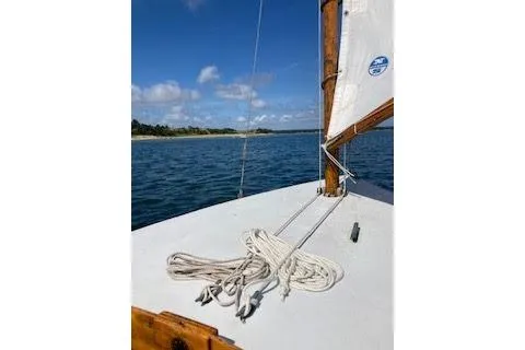 Slide: The Image of 1997 COMPASS CLASSIC Catboat sailing on calm waters under a clear blue sky. - 14