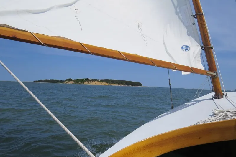 Slide: The Image of Sailing a 1997 COMPASS CLASSIC Catboat near a scenic island under clear blue skies. - 3