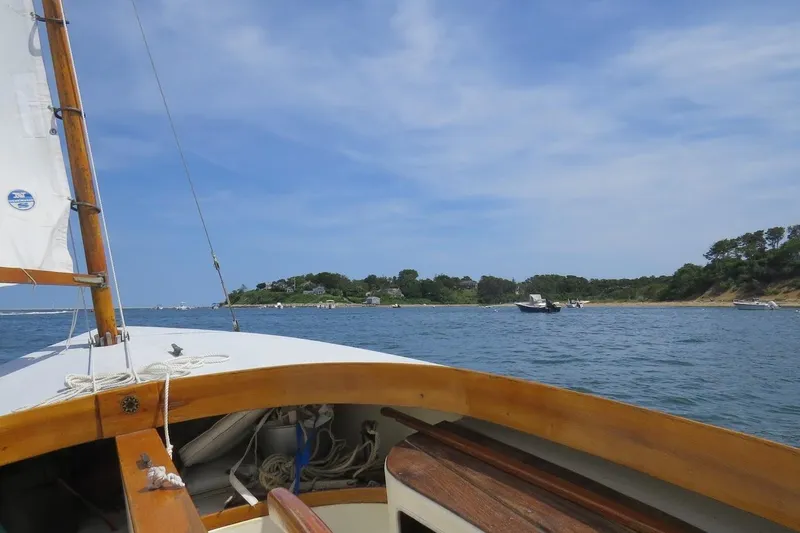 Slide: The Image of Sailing a 1997 COMPASS CLASSIC Catboat near a scenic coastline under a clear blue sky. - 7