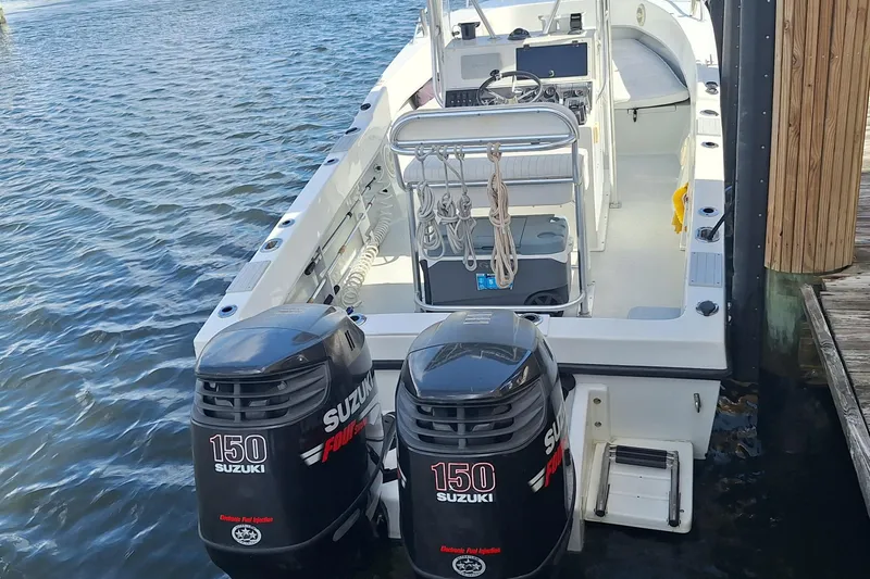 Slide: The Image of 2001 Dusky 252 Open Fisherman boat with twin Suzuki 150 engines docked on water. - 2