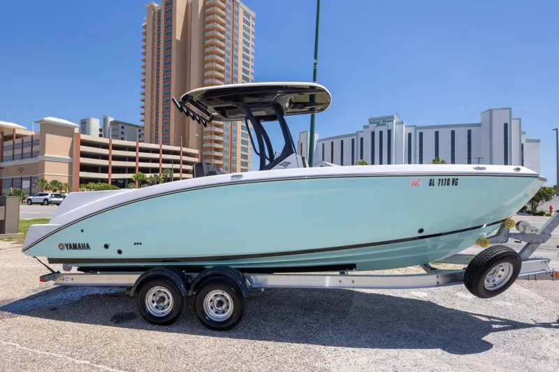 Slide: The Image of 2025 Yamaha Boats 255 FSH Sport E on trailer, urban backdrop, sunny day. - 10