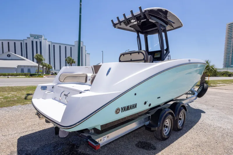 Slide: The Image of 2025 Yamaha Boats 255 FSH Sport E on trailer, parked near modern buildings. - 11