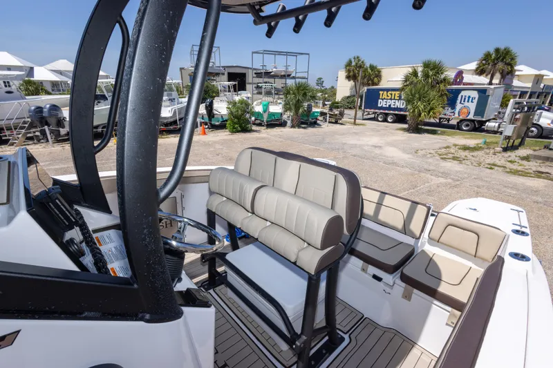 Slide: The Image of 2025 Yamaha Boats 255 FSH Sport E interior with seating and helm, docked outdoors. - 41
