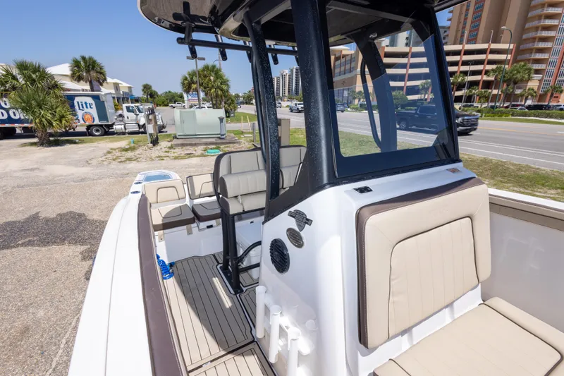 Slide: The Image of 2025 Yamaha Boats 255 FSH Sport E interior with seating and console, parked near a road. - 43