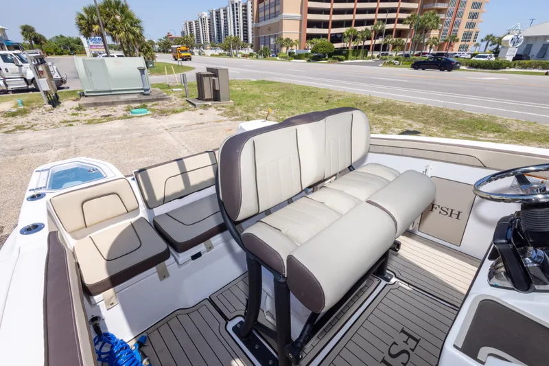 Slide: The Image of 2025 Yamaha Boats 255 FSH Sport E interior with seating and steering wheel, parked near road. - 45