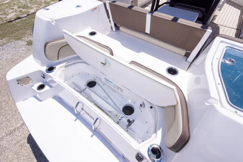 Slide: The Image of 2025 Yamaha Boats 255 FSH Sport E, open storage compartment, sleek design, white and brown seating. - 55