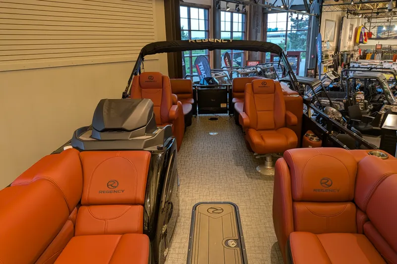 Slide: The Image of Luxurious 2026 Regency 230 DL pontoon boat with plush red seating in showroom. - 3