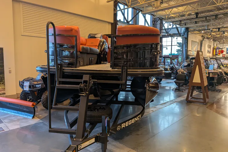 Slide: The Image of 2026 Regency 230 DL pontoon boat displayed in a showroom with modern interiors. - 2