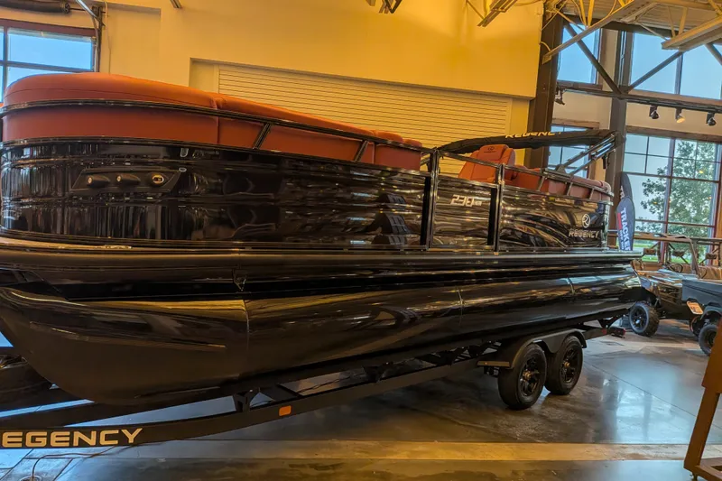 The Image of 2026 Regency 230 DL pontoon boat displayed indoors on a trailer. - 0