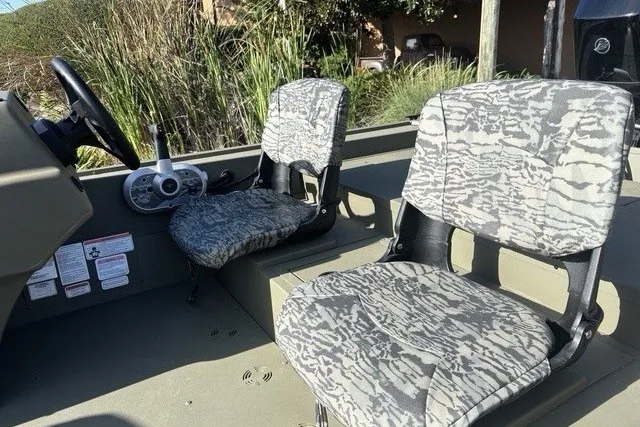 Slide: The Image of 2026 Tracker Grizzly 1754 SC boat interior with camo-patterned seats and steering console. - 3