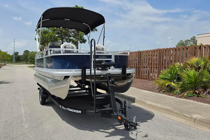 Slide: The Image of 2026 Sun Tracker Bass Buggy 18 DLX pontoon boat on trailer, parked outdoors. - 10