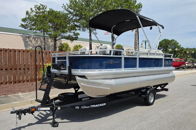 Slide: The Image of 2026 Sun Tracker Bass Buggy 18 DLX pontoon boat on trailer, parked outdoors. - 13