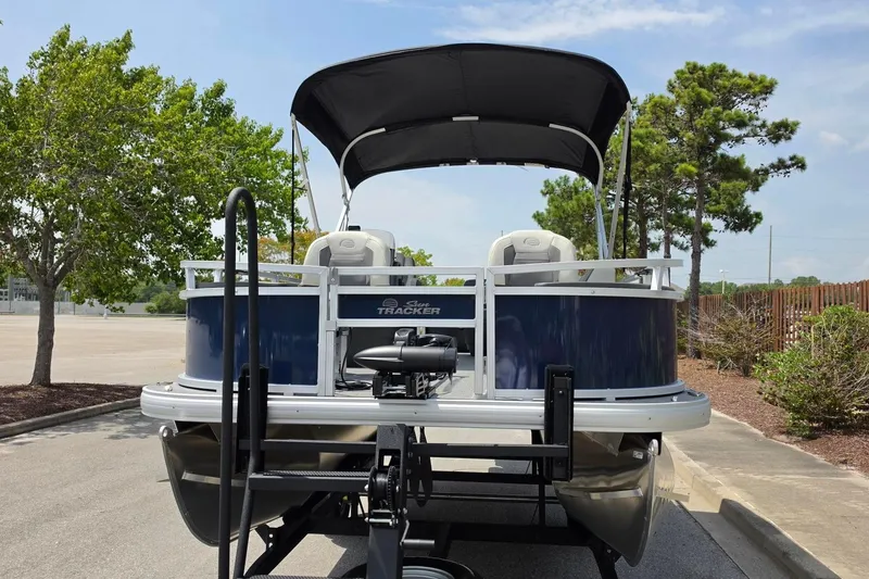Slide: The Image of 2026 Sun Tracker Bass Buggy 18 DLX pontoon boat on trailer, parked outdoors. - 9