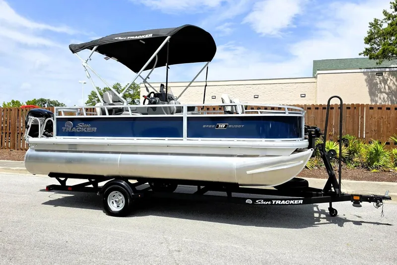 Slide: The Image of 2026 Sun Tracker Bass Buggy 18 DLX pontoon boat on trailer, parked outdoors. - 6
