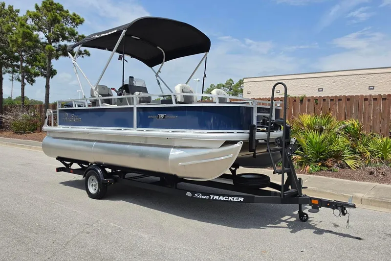 Slide: The Image of 2026 Sun Tracker Bass Buggy 18 DLX pontoon boat on trailer, parked outdoors. - 7